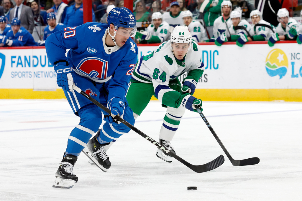 Colorado Avalanche's Ross Colton (20) moves the puck in front of Carolina Hurricanes' Joel Nystrom (64) during the first period of an NHL hockey game in Raleigh, N.C., Saturday, Jan. 3, 2026. (AP Photo/Karl DeBlaker)