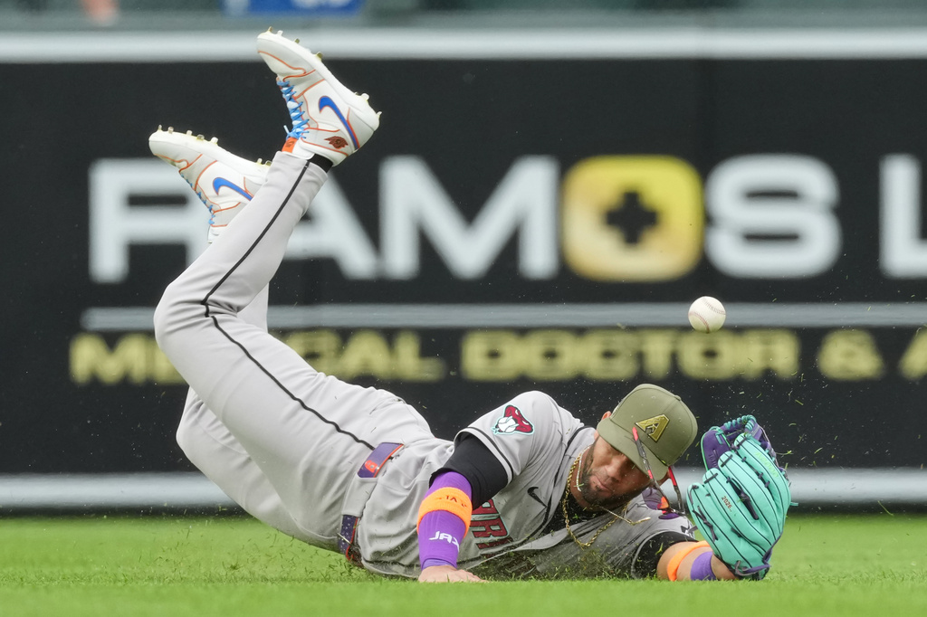 Arizona Diamondbacks left fielder Lourdes Gurriel Jr. has the ball pop out of his glove while tryig to field an RBI single off the bt of Colorado Rockies' Mickey Moniak in the first inning of a baseball game Saturday, May 16, 2026, in Denver. (AP Photo/David Zalubowski)