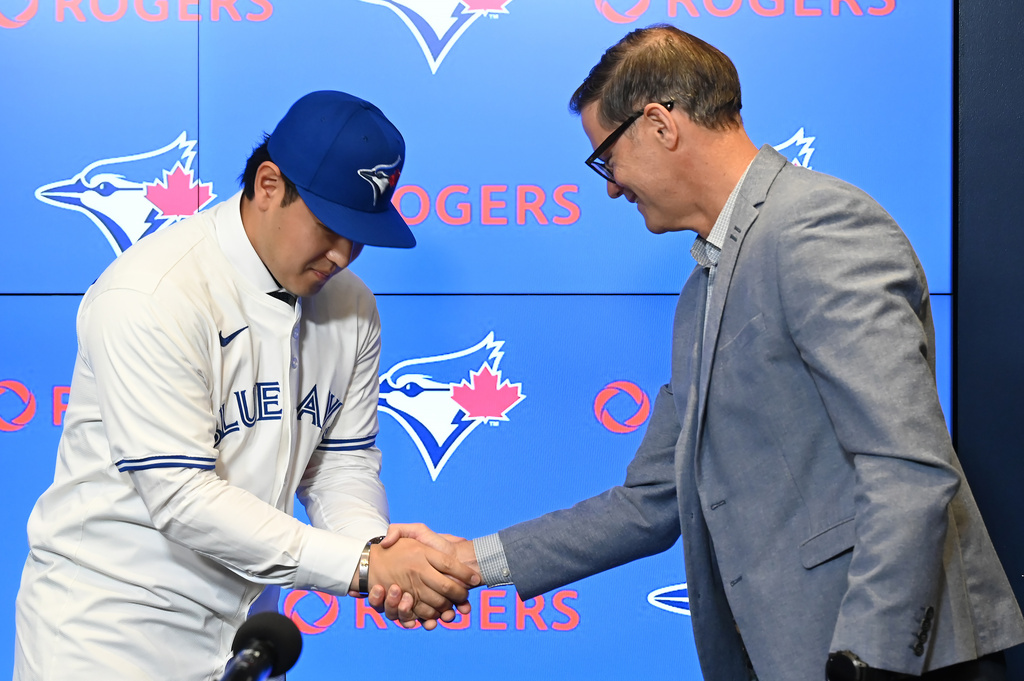 Kazuma Okamoto, left, shakes hands with Toronto Blue Jays general manager Ross Atkins at an introductory press conference at Rogers Centre in Toronto, Canada, on Tuesday, Jan. 6, 2026. (Jon Blacker/The Canadian Press via AP)