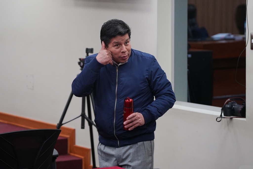 Former President Pedro Castillo, who faces charges of rebellion and other crimes against the state, jokingly makes a call me hand sign inside a courtroom while attending his sentence hearing at a police base on the outskirts of Lima, Peru, Thursday, Nov. 27, 2025. (AP Photo/Guadalupe Pardo)