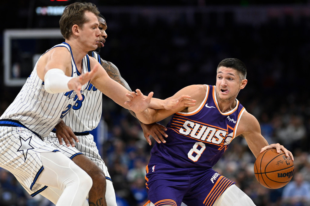 Phoenix Suns guard Grayson Allen (8) is defended by Orlando Magic forward Moritz Wagner, left, and forward Jamal Cain (8) during the first half of an NBA basketball game, Tuesday, March 31, 2026, in Orlando, Fla. (AP Photo/Phelan M. Ebenhack)