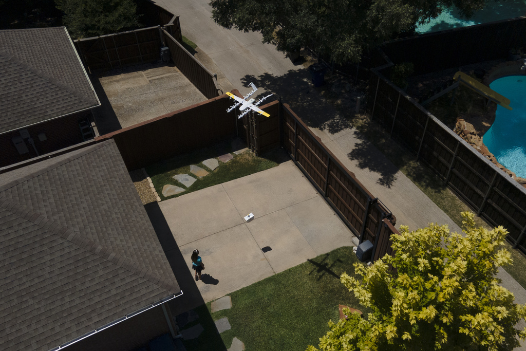 Julep Toth, 9, looks at a drone as it arrives at her house with a delivery, Thursday, July 31, 2025, in Frisco, Texas. (AP Photo/Julio Cortez)