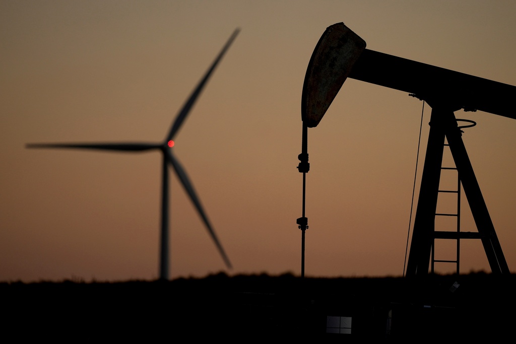 FILE - A pumpjack operates in the foreground while a wind turbine at the Buckeye Wind Energy wind farm rises in the distance, Sept. 30, 2024, near Hays, Kan. (AP Photo/Charlie Riedel, File)