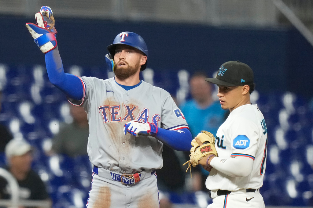 Texas Rangers' Brandon Nimmo, left, reacts after hitting a triple as Miami Marlins third baseman Javier Sanoja, right, looks on during the ninth inning of a baseball game, Tuesday, June 23, 2026, in Miami. (AP Photo/Lynne Sladky)