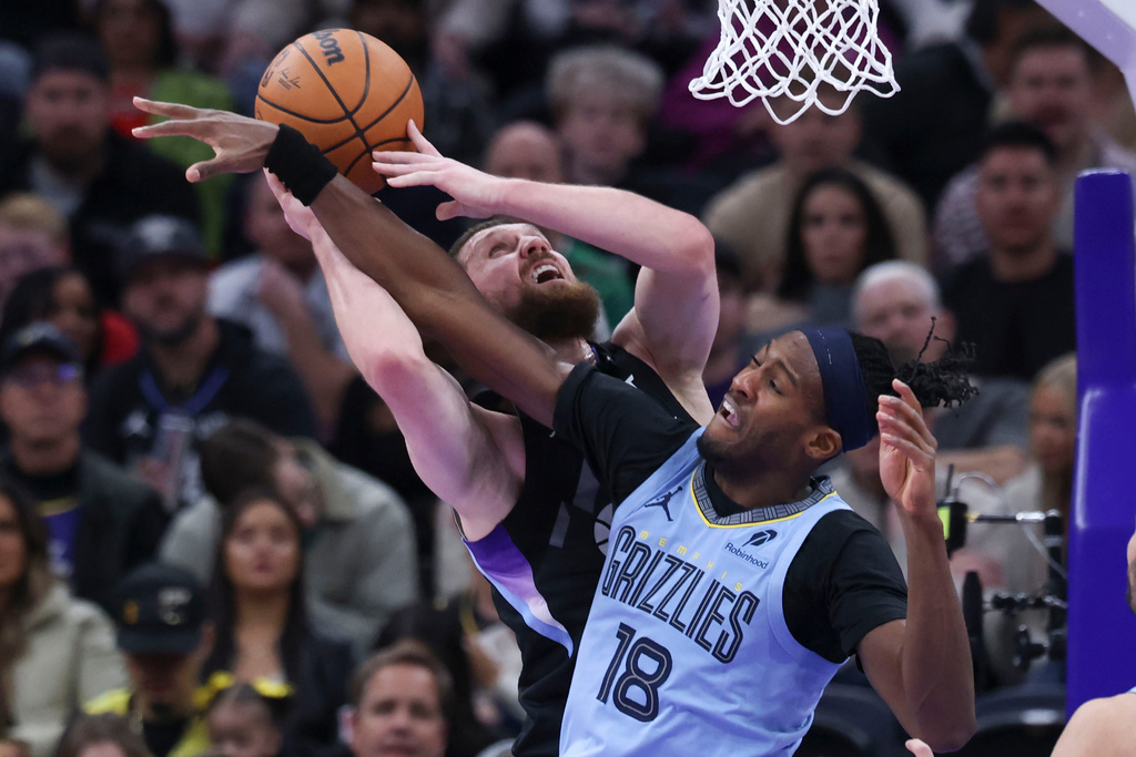 Utah Jazz guard Svi Mykhailiuk, left, is fouled by Memphis Grizzlies forward Olivier-Maxence Prosper (18) while going to the basket during the first half of an NBA basketball game, Tuesday, Dec. 23, 2025, in Salt Lake City. (AP Photo/Rob Gray)