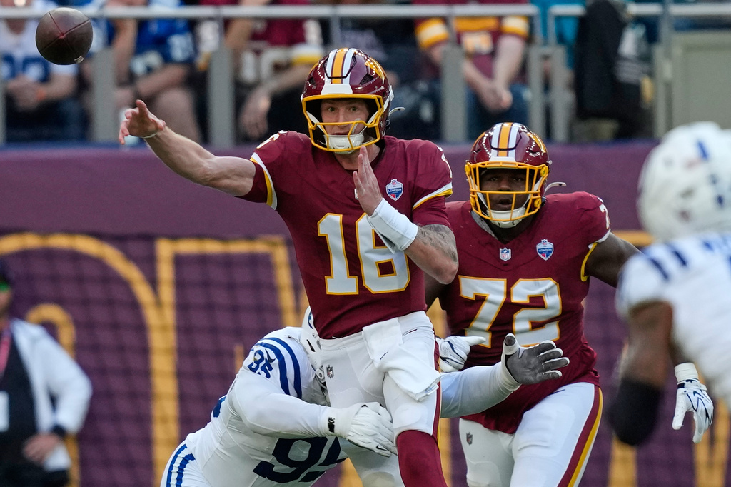 Washington Commanders quarterback Athan Kaliakmanis (16) throws a pass challenged vy Indianapolis Colts defensive tackle Adetomiwa Adebawore (95) during an NFL football game against Indianapolis Colts in London, Sunday, Oct. 4, 2026. (AP Photo/David J. Phillip)