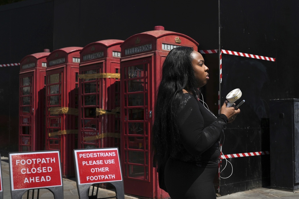FILE - A woman cools herself with a fan during a hot day in London, June 26, 2024. (AP Photo/Kin Cheung, File)
