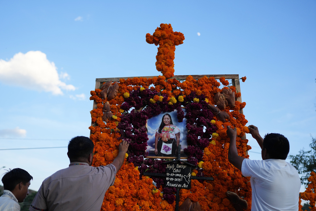 Relatives place flowers on an altar honoring Nayely Domingo Ceras during the Day of the Dead celebrations at the cemetery of Tzintzuntzan, Michoacan state, Mexico, Friday, Oct. 31, 2025. (AP Photo/Eduardo Verdugo)