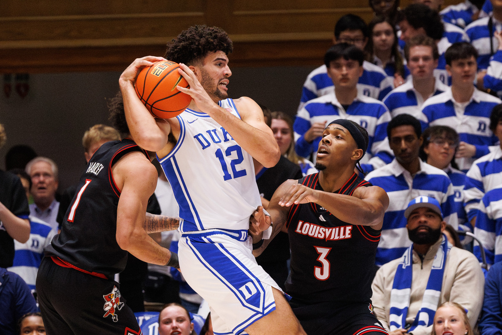 Duke's Cameron Boozer (12) handles the ball as Louisville's Ryan Conwell (3) defends during the first half of an NCAA college basketball game in Durham, N.C., Monday, Jan. 26, 2026. (AP Photo/Ben McKeown)