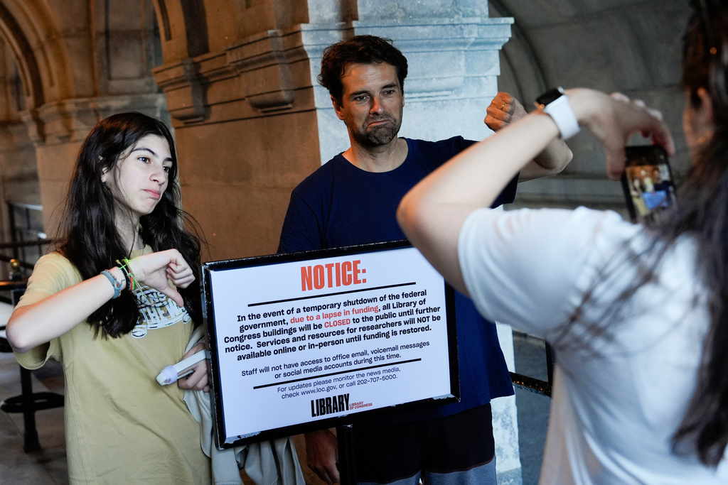 People take photos with a sign announcing that the Library of Congress is closed, on the first day of a partial government shutdown, Wednesday, Oct. 1, 2025, in Washington. (AP Photo/Julia Demaree Nikhinson)