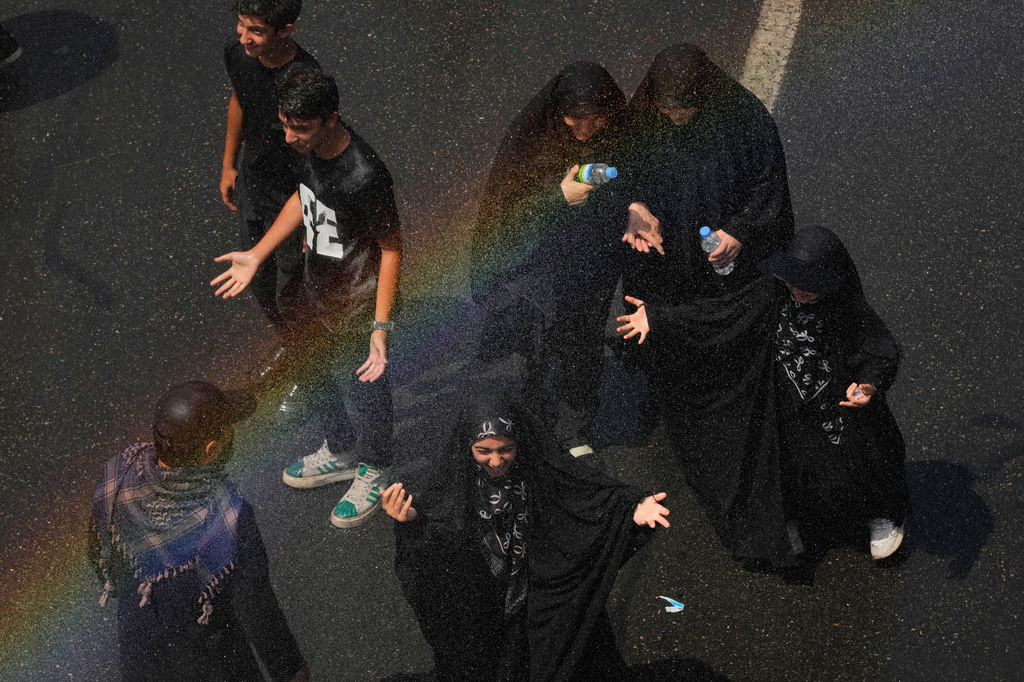 Mourners cool off under a spray of water as they walk to the Imam Khomeini Mosalla Grand Mosque during the dayslong funeral ceremonies for the late Iranian Supreme Leader Ayatollah Ali Khamenei in Tehran, Iran, Saturday, July 4, 2026. (AP Photo/Vahid Salemi)