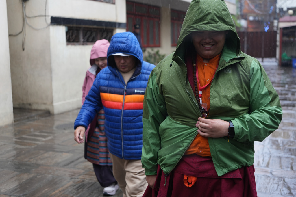 U.S.-born Buddhist lama Jalue Dorje walks in the rain with his parents, Dorje Tsegyal and Dechen Wangmo, during a 12-day series of rituals and teachings at Shechen Monastery in Kathmandu, Nepal, on Wednesday, April 8, 2026. (AP Photo/Luis Andres Henao)