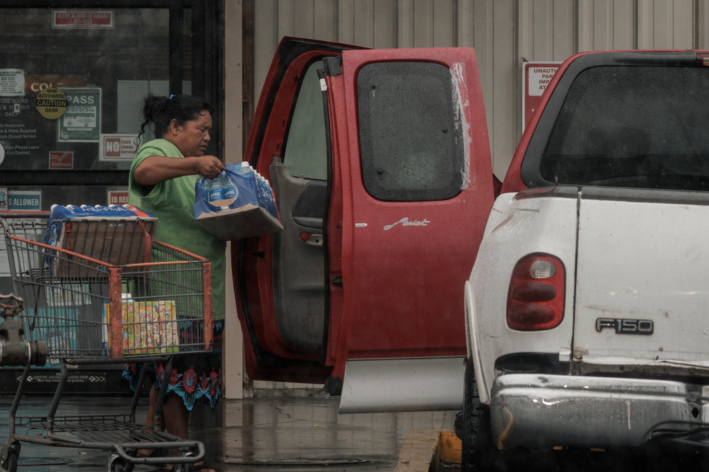A resident carries supplies to a vehicle during Hurricane Lala in Hawaiian Ocean View, Hawaii, Saturday, Aug. 15, 2026. (Stephen Lam/San Francisco Chronicle via AP)