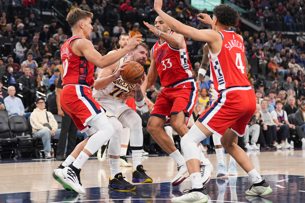 Los Angeles Lakers' Luka Doncic (77) is defended by Los Angeles Clippers' Bogdan Bogdanovic (10), Nicolas Batum (33) and Kobe Sanders (4) during the first half of an NBA basketball game Saturday, Dec. 20, 2025, in Inglewood, Calif. (AP Photo/Jae C. Hong)