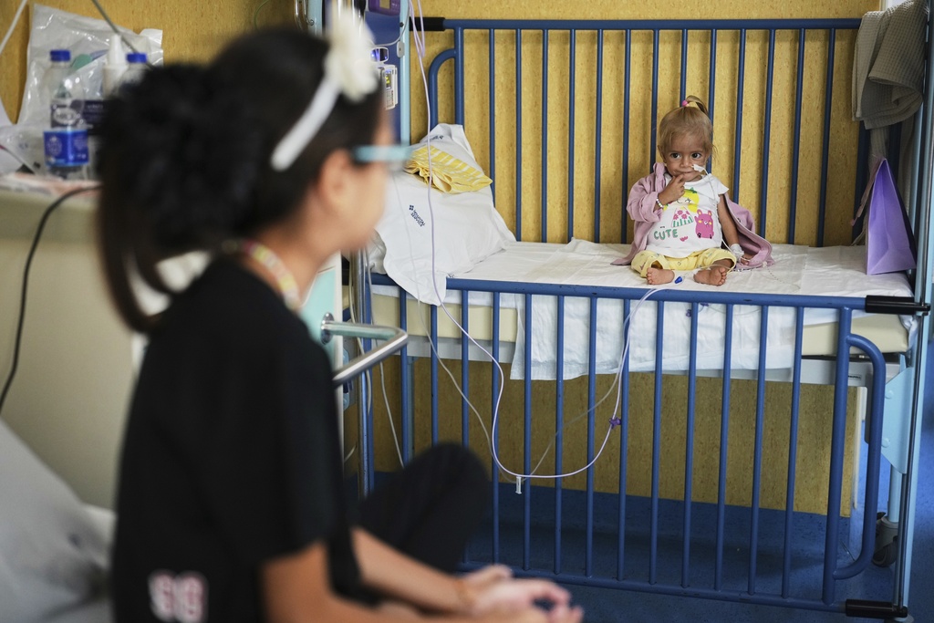 Judi Qudeih, 10, looks at her sister Shamm Qudeih, 2, as Shamm sits on her bed at the Santobono Pausilipon Children's Hospital in Naples, southern Italy, Tuesday, Sept. 2, 2025, where she is being treated. (AP Photo/Andrew Medichini)