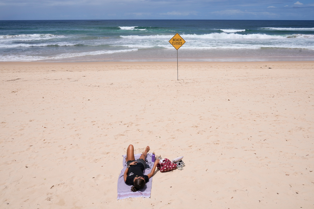 A lone sun bather relaxes at North Steyne Beach in Sydney, Tuesday, Jan. 20, 2026, after a series of shark attacks. (AP Photo/Rick Rycroft)