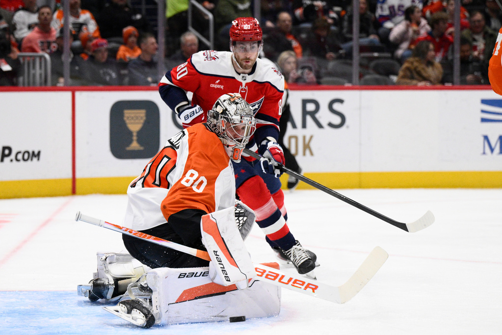 Philadelphia Flyers goaltender Dan Vladar, front, stops the puck next to Washington Capitals left wing Pierre-Luc Dubois, back, during the second period of an NHL hockey game, Wednesday, Feb. 25, 2026, in Washington. (AP Photo/Nick Wass)
