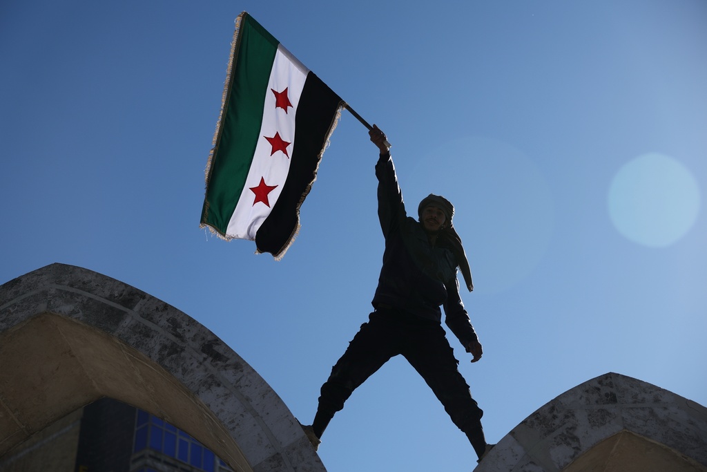 FILE - A soldier waves a Syrian flag amid celebrations a day after Syrian government troops took control of Raqqa from the Syrian Democratic Forces (SDF), at Al-Naeem roundabout in central Raqqa, northeastern Syria, Monday, Jan. 19, 2026. (AP Photo/Ghaith Alsayed, File)