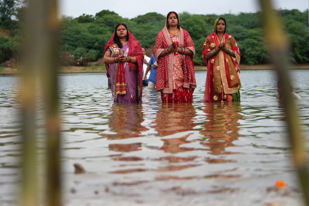 Hindu devotees perform rituals at sunset in the River Sabarmati during Chhath Puja festival in Ahmedabad, India, Monday, Oct. 27, 2025. (AP Photo/Ajit Solanki)