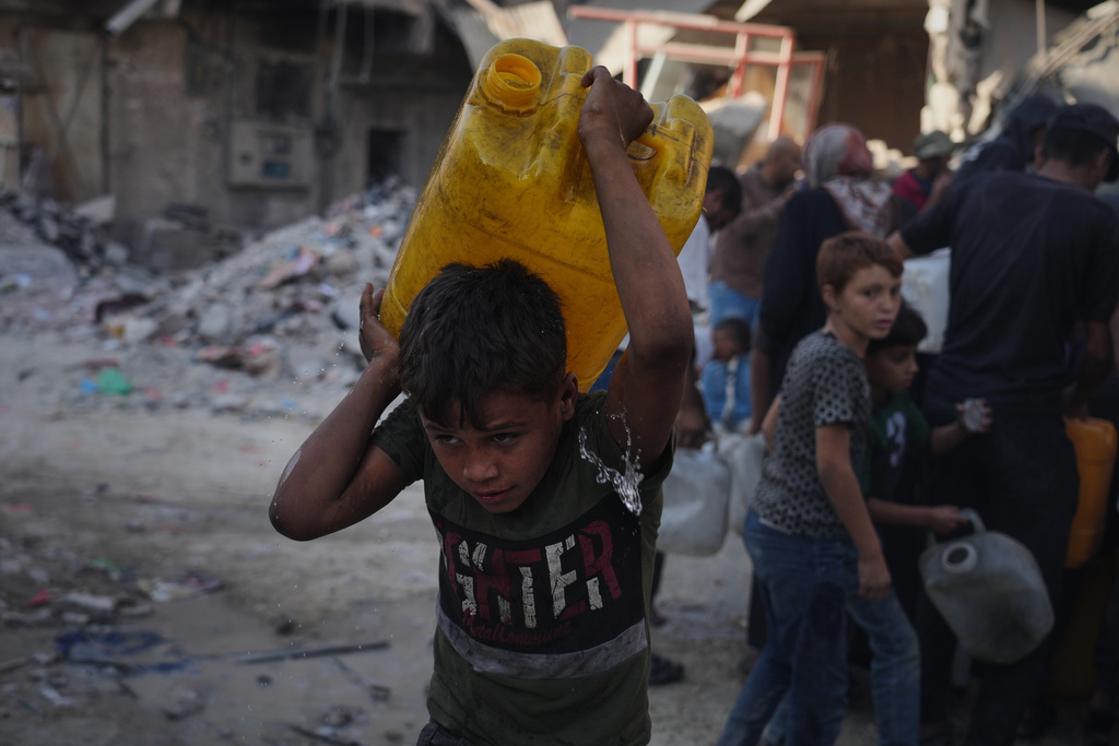Palestinians carry jerrycans with water they collect from a truck in Gaza City, Thursday, Oct. 16, 2025. (AP Photo/Jehad Alshrafi)