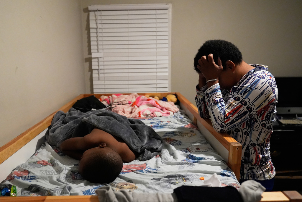 Sechita McNair tries to wake up her son Malachi McNair-Nesbitt early in Jonesboro, Ga., so he can travel to school in Atlanta on Aug. 4, 2025. (AP Photo/Brynn Anderson)
