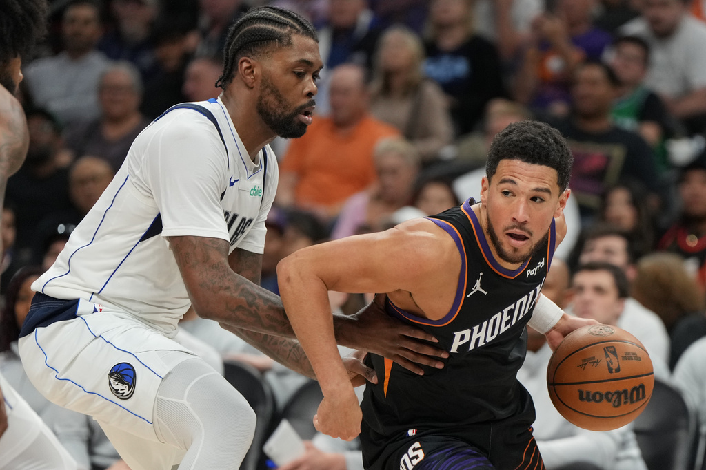 Phoenix Suns guard Devin Booker drives around Dallas Mavericks forward Naji Marshall during the second half of an NBA basketball game, Tuesday, Feb. 10, 2026, in Phoenix. (AP Photo/Rick Scuteri)