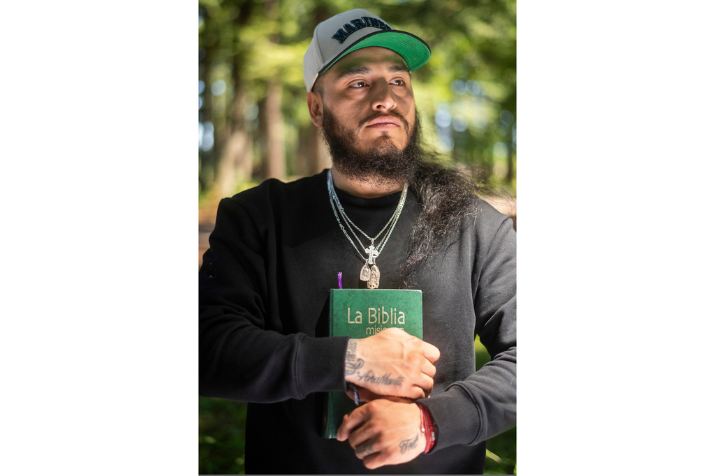 Gabriel Martinez Garcia, 30, holds a Bible close to his chest as tattoos of his parents are visible on his wrists, in Tenino, Wash., on Sunday, June 14, 2026. (AP Photo/Akash Pamarthy)