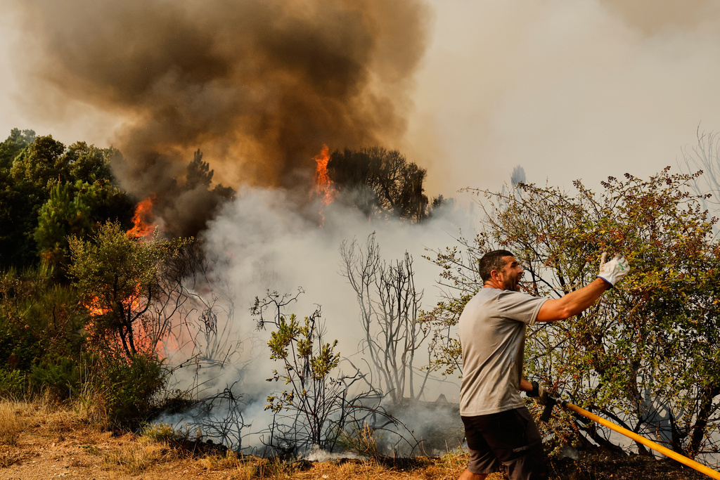 A man tries to put out a wildfire in Larouco, northwestern Spain, Wednesday, Aug. 13, 2025. (AP Photo/Lalo R. Villar)