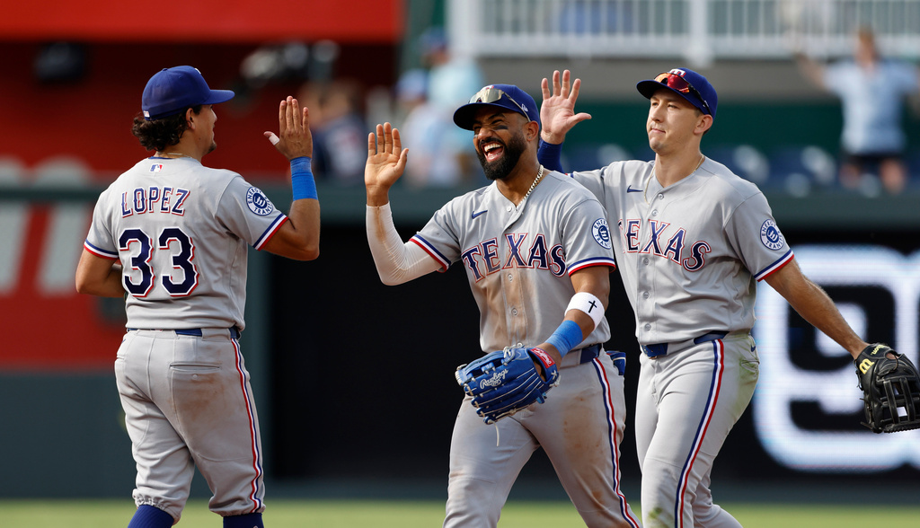 Texas Rangers' Nicky Lopez (33) Ezequiel Duran, center, and Wyatt Langford, right, celebrate at the end of a baseball game against the Kansas City Royals in Kansas City, Mo., Thursday, June 11, 2026. (AP Photo/Colin E. Braley)