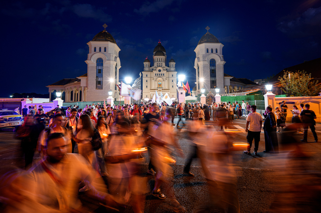 People walk, backdropped by the National Cathedral, during the Procession of Lights, part of a four-day program of the International Meeting of Orthodox Youth (ITO), in Bucharest, Romania, Wednesday, Sept. 2, 2026. (AP Photo/Andreea Alexandru)
