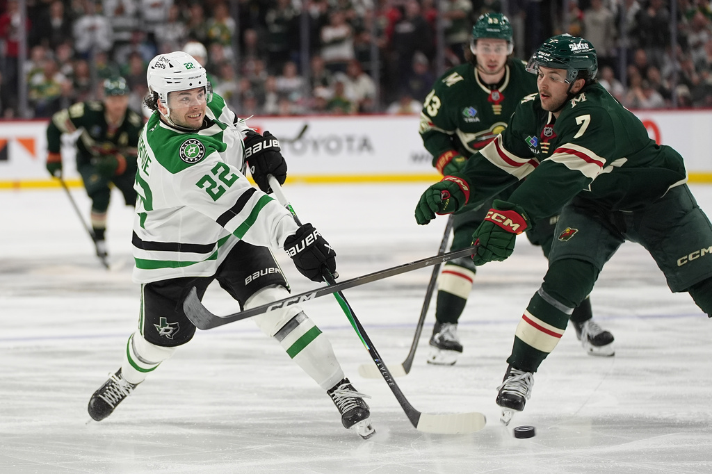 Dallas Stars center Mavrik Bourque (22) shoots as Minnesota Wild defenseman Brock Faber (7) defends during overtime of Game 3 in the first round of the NHL Stanley Cup hockey playoffs early morning Thursday, April 23, 2026, in St. Paul, Minn. (AP Photo/Abbie Parr)