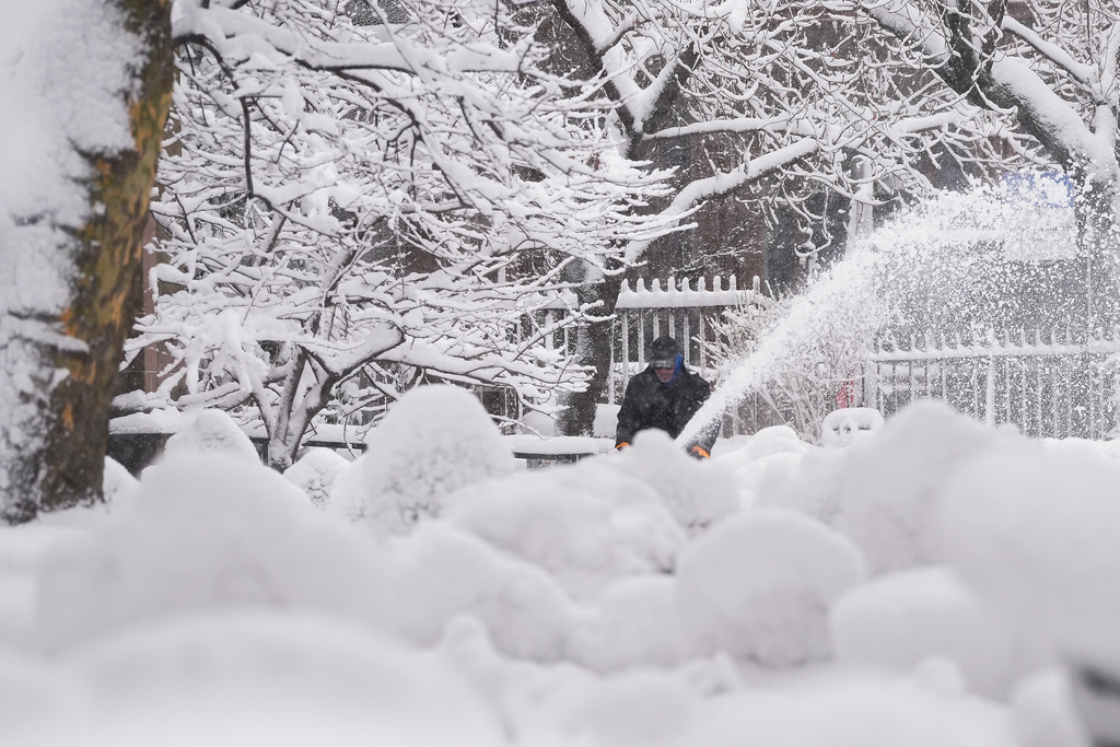 A groundskeeper clears snow from the walkways inside the Trinity Church graveyard in lower Manhattan during a snow storm, Monday, Feb. 23, 2026, in New York. (AP Photo/Seth Wenig)
