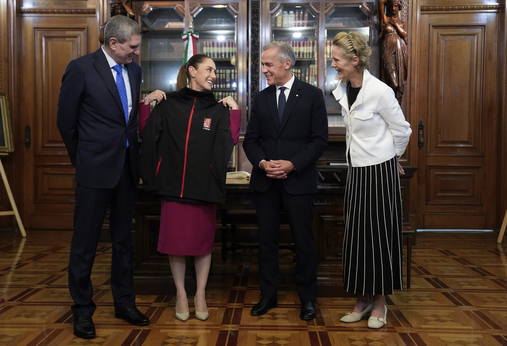 Diana Fox Carney, right, and Jesus Maria Tarriba, left, look on as Canada's Prime Minister Mark Carney presents Mexican President Claudia Sheinbaum with a World Cup sweater before a meeting at the National Palace in Mexico City, Thursday, Sept. 18, 2025. (Adrian Wyld/The Canadian Press via AP)