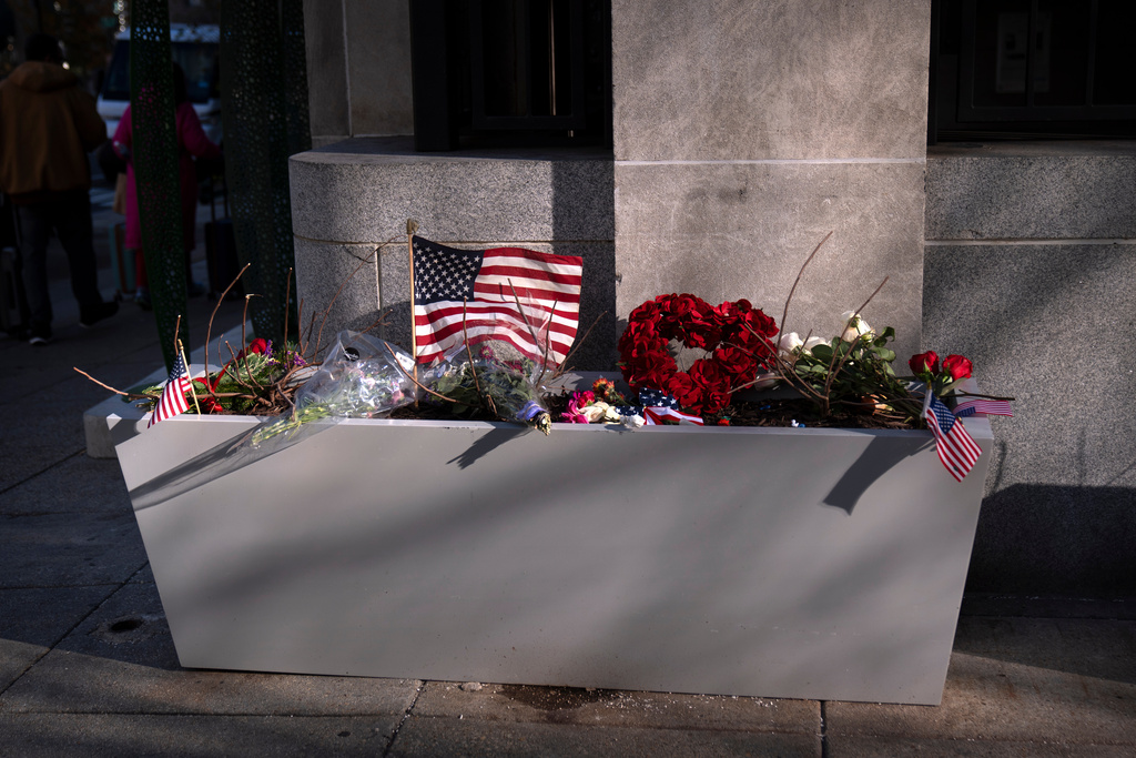 A small memorial of flags, flowers, other items are seen in a planter, Friday, Nov. 28, 2025, near the site where two National Guard members were shot in Washington. (AP Photo/Mark Schiefelbein)