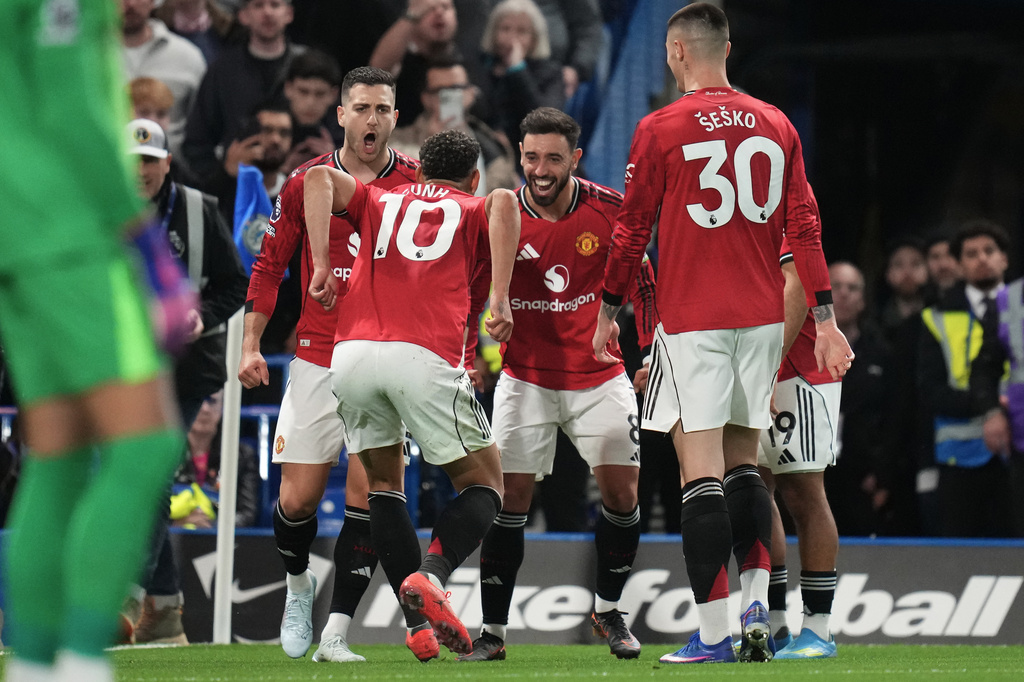 Manchester United's Matheus Cunha celebrates with teammates after scoring the opening goal during the English Premier League soccer match between Chelsea and Manchester United in London, Saturday, April 18, 2026. (AP Photo/Kirsty Wigglesworth)