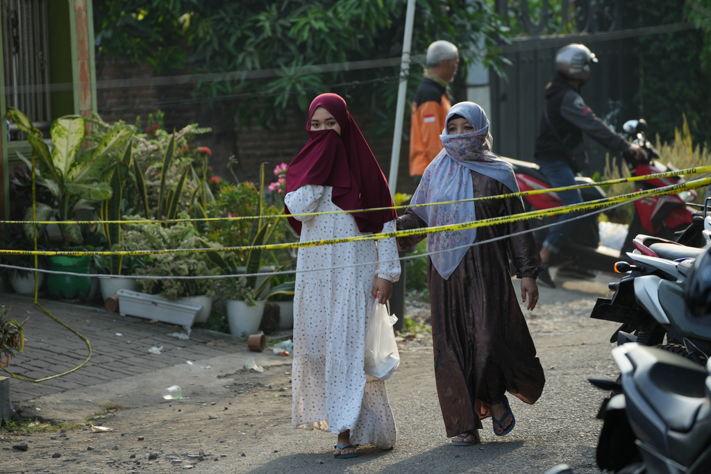 Women walk near the Islamic boarding school compound where a building collapsed, in Sidoarjo, East Java, Indonesia, Saturday, Oct. 4, 2025. (AP Photo/Achmad Ibrahim)