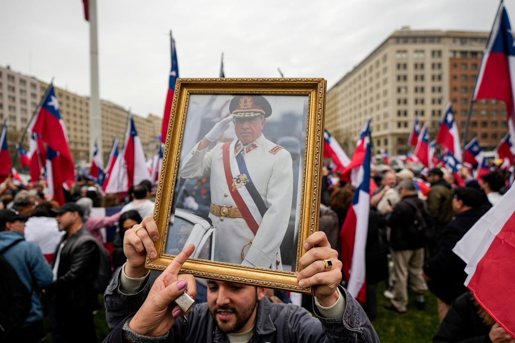 FILE - A group in favor of Gen. Augusto Pinochet celebrate the 50th anniversary of a military coup led by Pinochet, near La Moneda presidential palace, in Santiago, Chile, Sept. 9, 2023. (AP Photo/Esteban Felix, File)