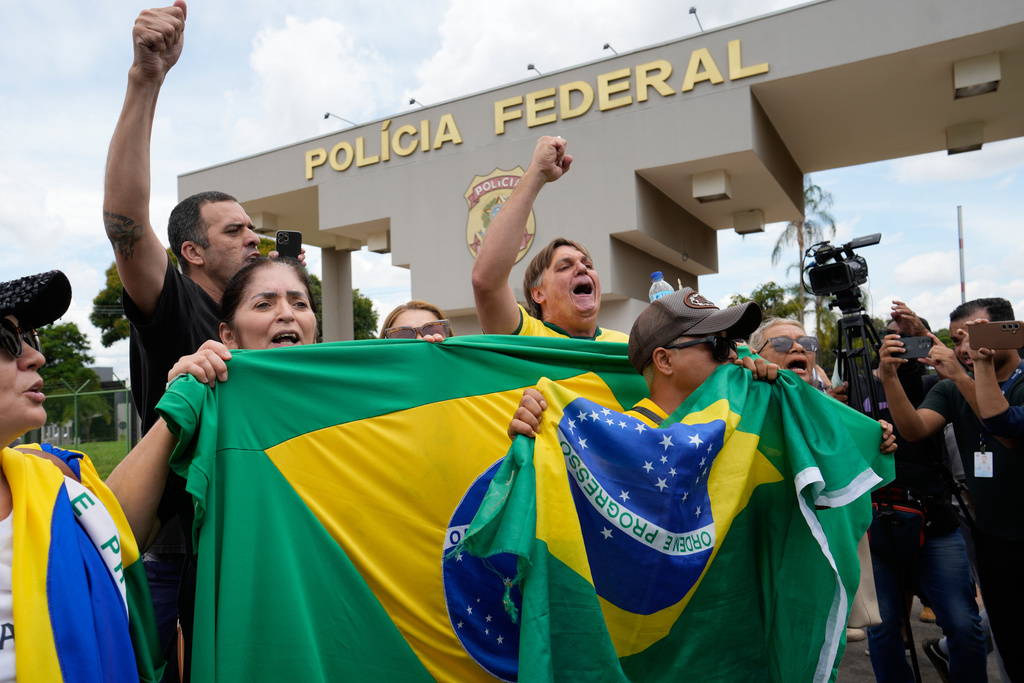 Supporters protest against the arrest of Brazil's former President Jair Bolsonaro outside the Federal Police headquarters, where Bolsonaro is under arrest in Brasilia, Brazil, Saturday, Nov. 22, 2025. Brazil's Federal Police arrested Bolsonaro preemptively on Saturday, days before he was due to start serving his 27-year-plus prison sentence for leading a coup attempt. (AP Photo/Eraldo Peres)