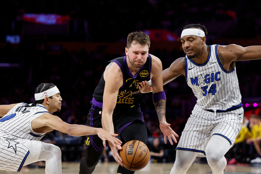Los Angeles Lakers guard Luka Doncic (77) runs with the ball while being guarded by Orlando Magic guard Anthony Black (0) and Orlando Magic center Wendell Carter Jr. (34) during the second half of an NBA basketball game Tuesday, Feb. 24, 2026, in Los Angeles. (AP Photo/Caroline Brehman)