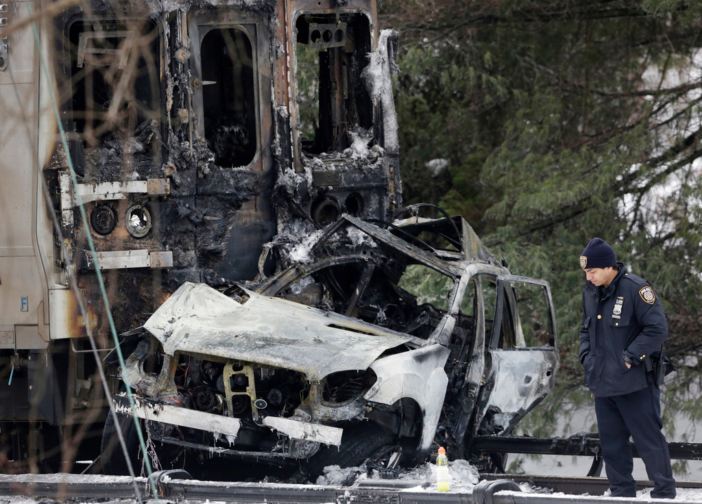 FILE - A police officer looks at an SUV that was crushed at the front of a Metro-North Railroad train, Feb. 4, 2015, in Valhalla, N.Y. (AP Photo/Mark Lennihan, File)