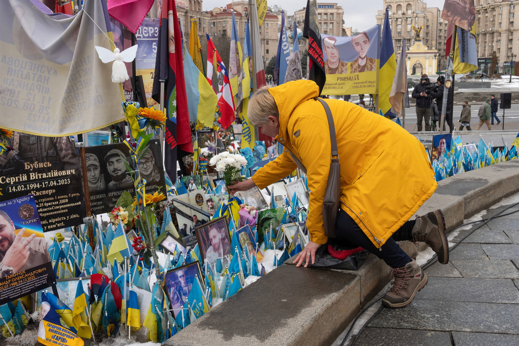 A woman place flowers at the memorial to the fallen Ukrainian soldiers on Independence Square to mark the fourth anniversary of Russia's full-scale invasion in Kyiv, Ukraine, Tuesday, Feb. 24, 2026. (AP Photo/Efrem Lukatsky)