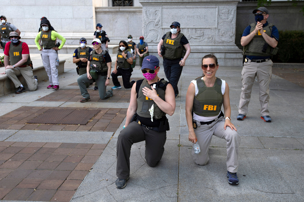 FILE - Federal Bureau of Investigation officers take a knee with demonstrators as they march on Pennsylvania Ave during a protest over the death of George Floyd on June 4, 2020, in Washington. (AP Photo/Jose Luis Magana, File)