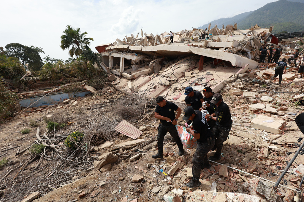 Police carry a body recovered from the rubble of a building in La Guaira, Venezuela, Thursday, June 25, 2026, a day after successive powerful earthquakes struck the country. (AP Photo/Javier Campos)