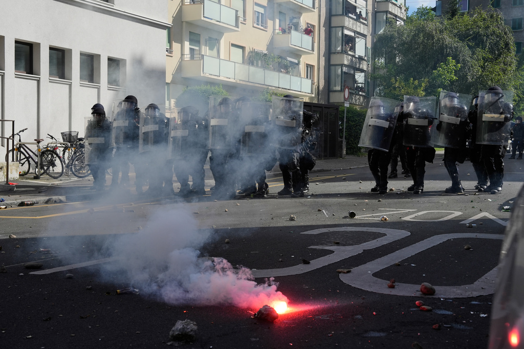 Police form a line in front of a burning flare during a "No G7" demonstration in Geneva, Switzerland, Sunday, June 14, 2026, ahead of the G7 summit scheduled to take place June 15-17. (AP Photo/Baz Ratner)