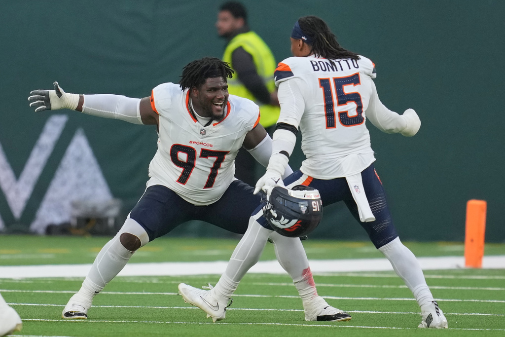 Denver Broncos defensive tackle Malcolm Roach (97) and Denver Broncos linebacker Nik Bonitto (15) celebrate after the NFL football game between the Denver Broncos and the New York Jets, Sunday, Oct. 12, 2025, in London. (AP Photo/Kin Cheung)