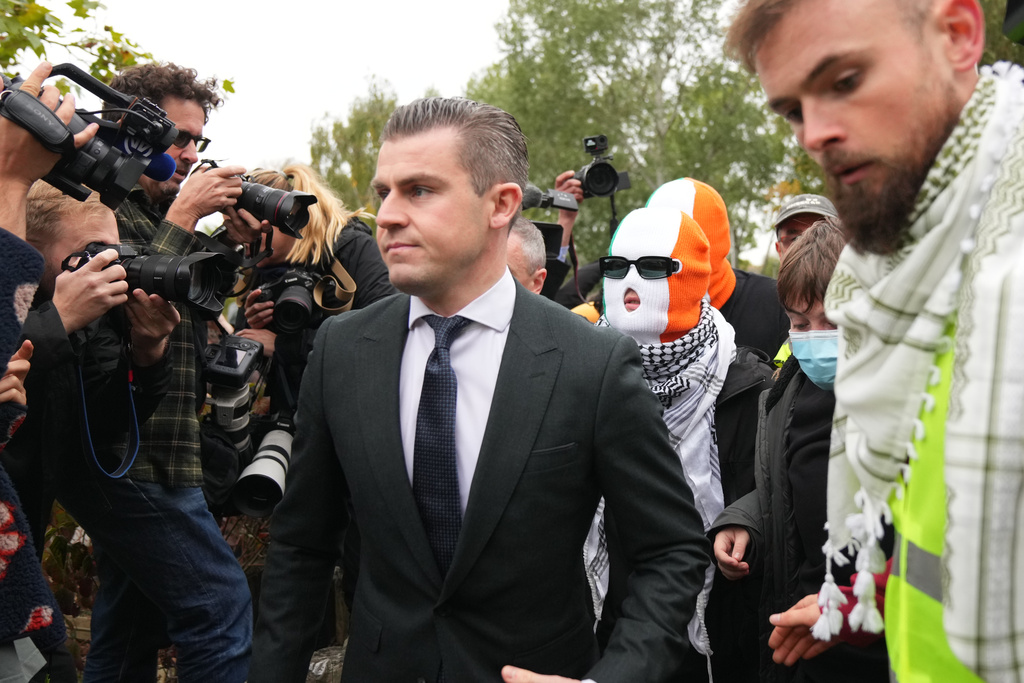 A person believed to be Liam Óg Ó hAnnaidh, aka Mo Chara, in a mask, a member of the Irish language band Kneecap, arrives at Woolwich Crown Court in London London, Friday, Sept. 26, 2025, where he is charged with a terrorism offence relating to displaying a flag in support of Hezbollah during a performance with the band in November 2024. (AP Photo/Joanna Chan)