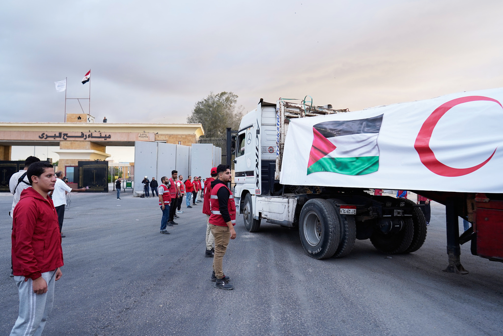 Egyptian Red Crecent members monitor trucks carrying humanitarian aid as they enter the Rafah crossing between Egypt and the Gaza Strip, following an agreement between Israel and Hamas on a ceasefire, Sunday, Oct. 12, 2025. (AP Photo/Mohamed Arafat)
