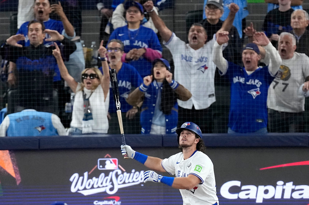 Toronto Blue Jays' Addison Barger watches his grand slam home run take flight as Los Angeles Dodgers' pitcher Anthony Banda, left, looks away uring the sixth inning in Game 1 of baseball's World Series, Friday, Oct. 24, 2025, in Toronto. (AP Photo/David J. Phillip)