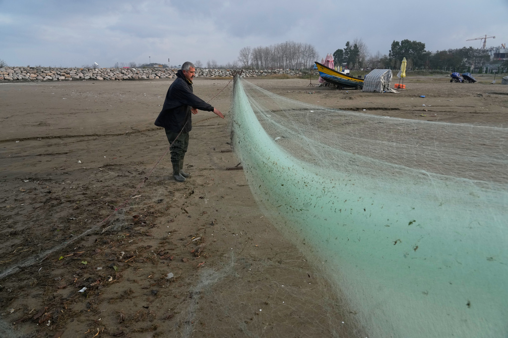 A fisherman prepares his net at the beach of the southern coast of the Caspian Sea outside the port city of Bandar Anzali, Iran, Tuesday, Dec. 23, 2025. (AP Photo/Vahid Salemi)