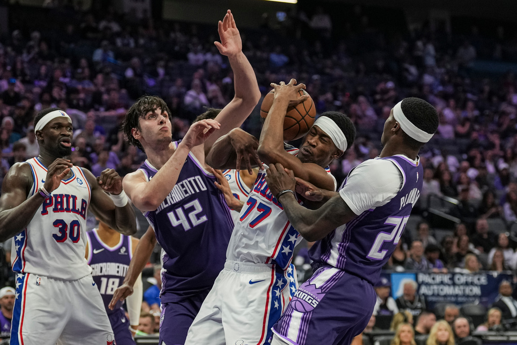 Sacramento Kings center Maxime Raynaud (42) and Philadelphia 76ers guard Vj Edgecombe (77) go for a rebound during the first half of an NBA basketball game, Thursday, March 19, 2026, in Sacramento, Calif. (AP Photo/Justine Willard)